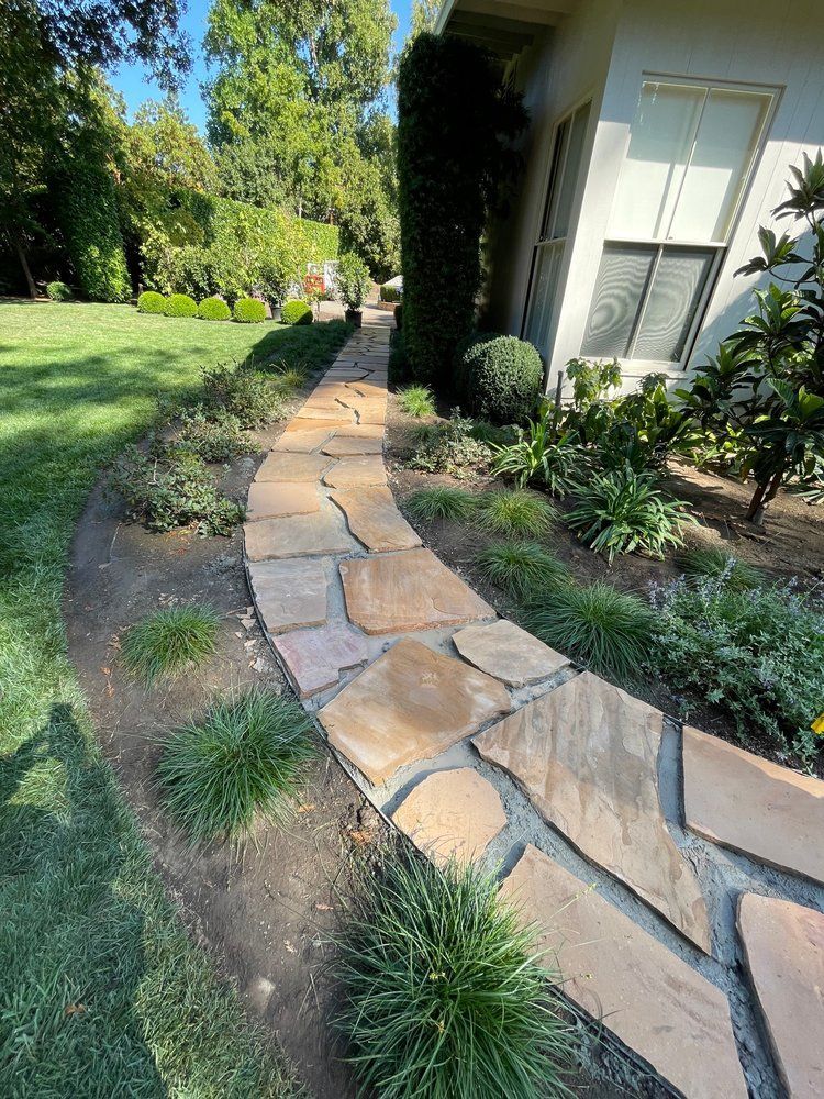 A stone walkway leading to a house in a yard.
