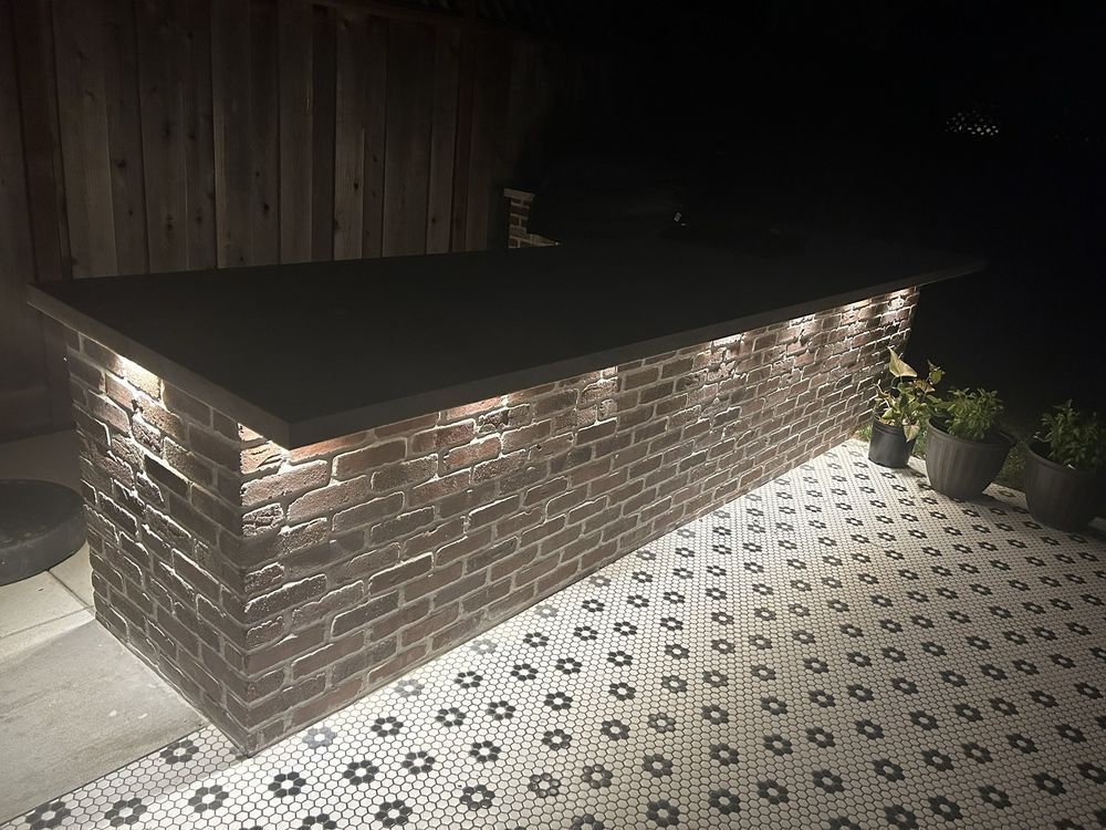 A brick bar with lights on it is sitting on a tiled floor.