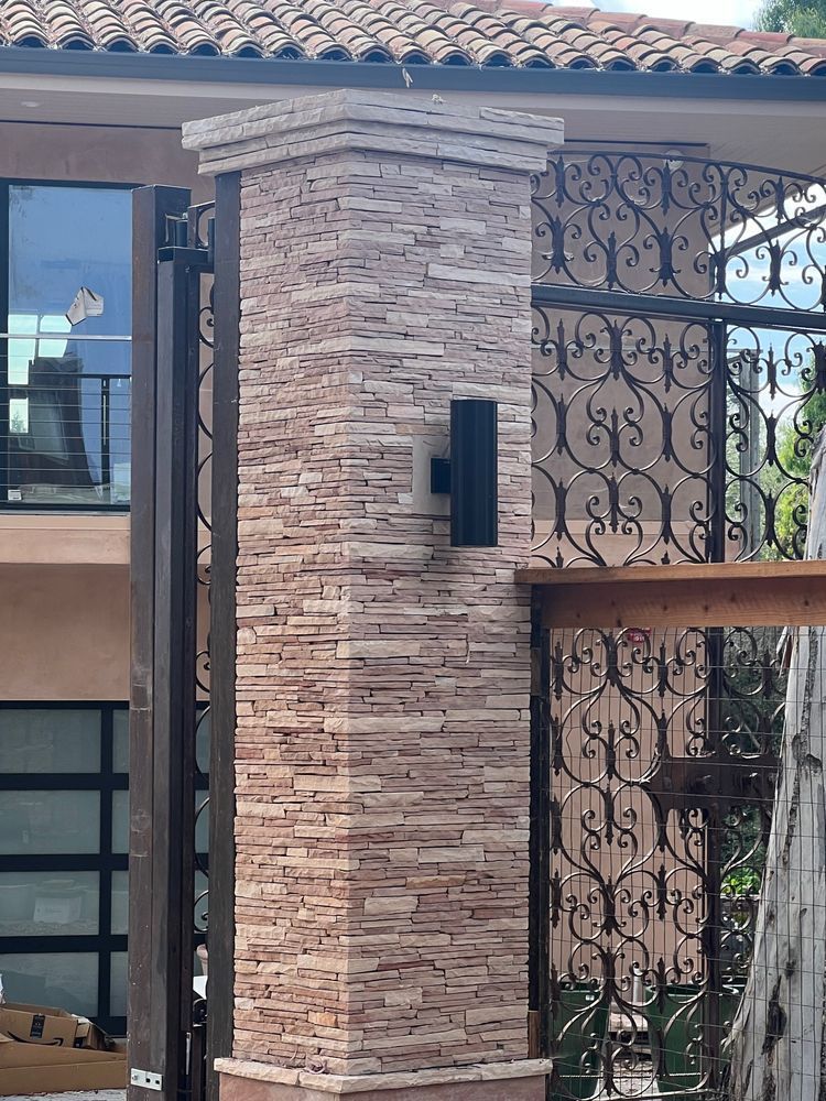 A house with a brick wall and a wrought iron gate