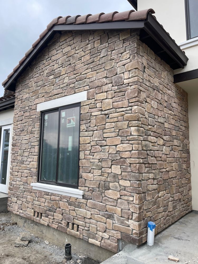 A stone wall with a window on the side of a house.