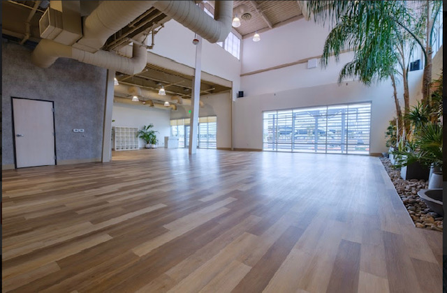 A large empty room with a wooden floor and lots of windows.