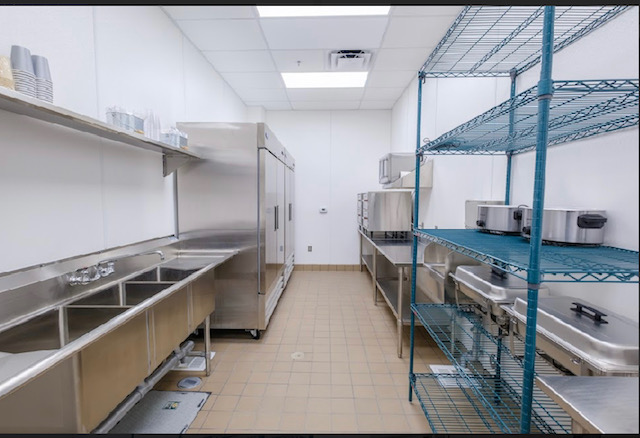 A kitchen with a lot of stainless steel appliances and shelves.