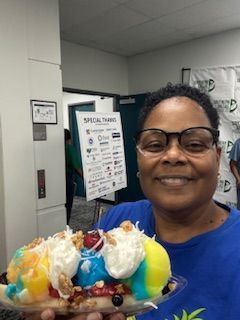 Woman holding a large banana split; smiling indoors near a 