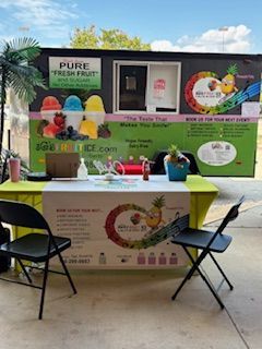 Fruit juice food truck with table and chairs set up outdoors.