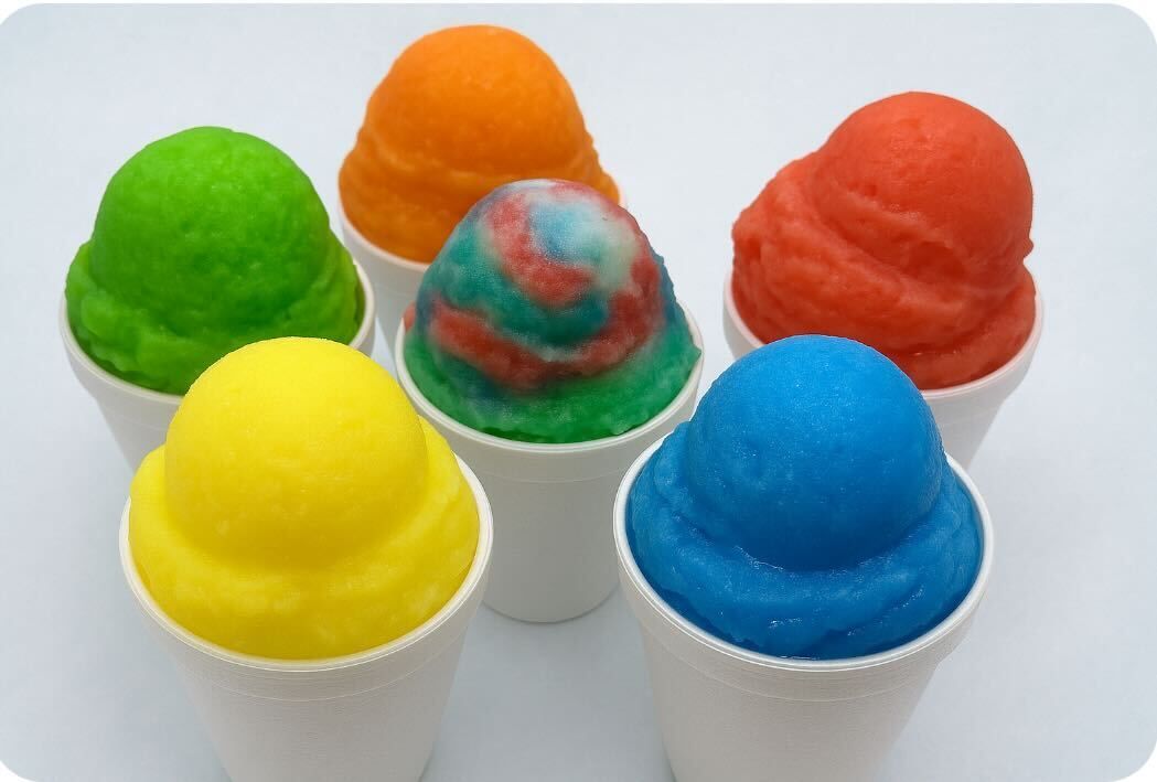 Colorful snow cones in white cups: green, orange, red, blue, yellow, and swirled.