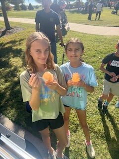 Two girls holding shaved ice, smiling outside.