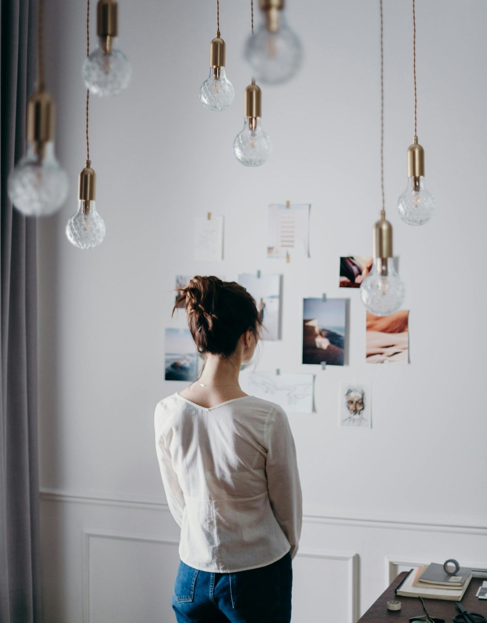 A woman is standing in front of a wall with pictures on it.