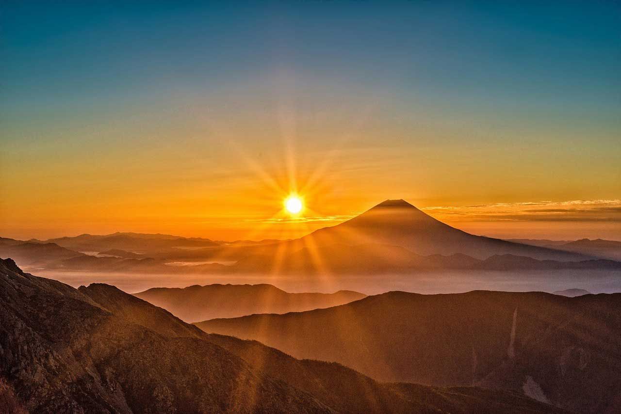 Golden Sunrise Over Mountain Silhouette And Layered Hills Under Clear Sky