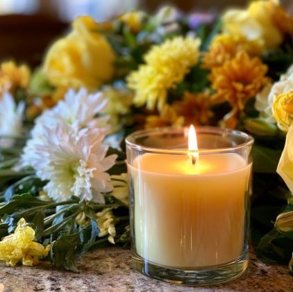 Memorial candle surrounded by yellow flowers at funeral service in Walla Walla, WA.