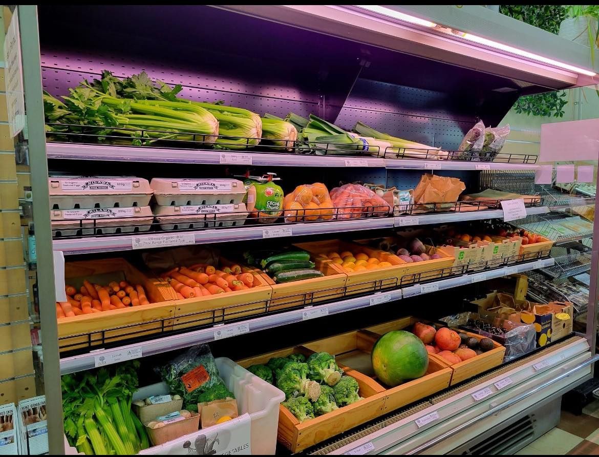 A refrigerator filled with fruits and vegetables in a grocery store.