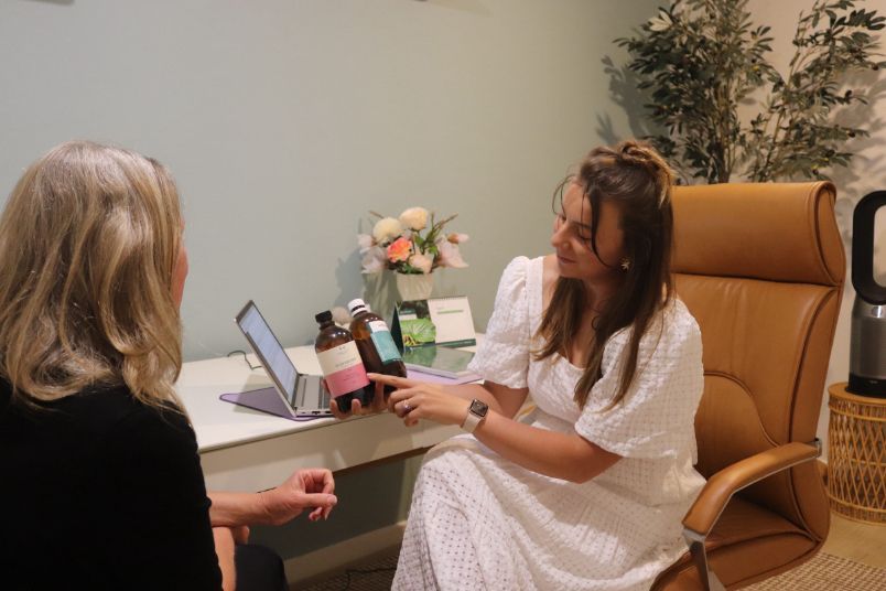 A woman is sitting at a desk talking to another woman.