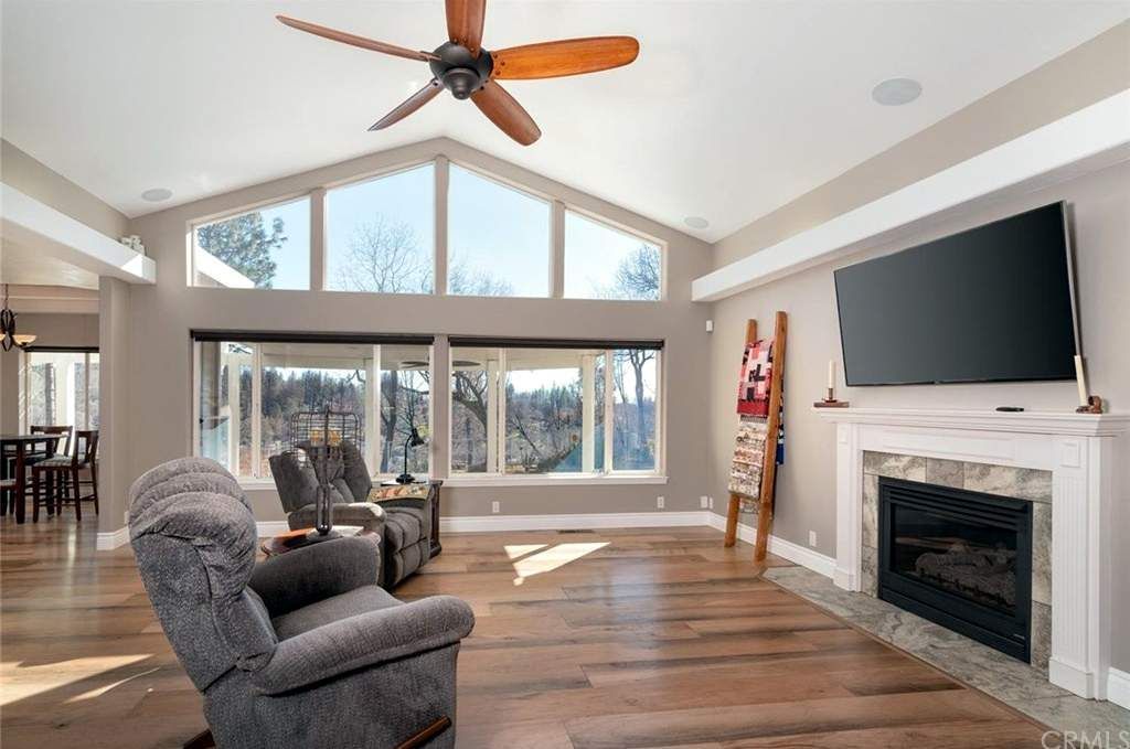 Living room with large windows, fireplace, wooden floor, and two recliners.
