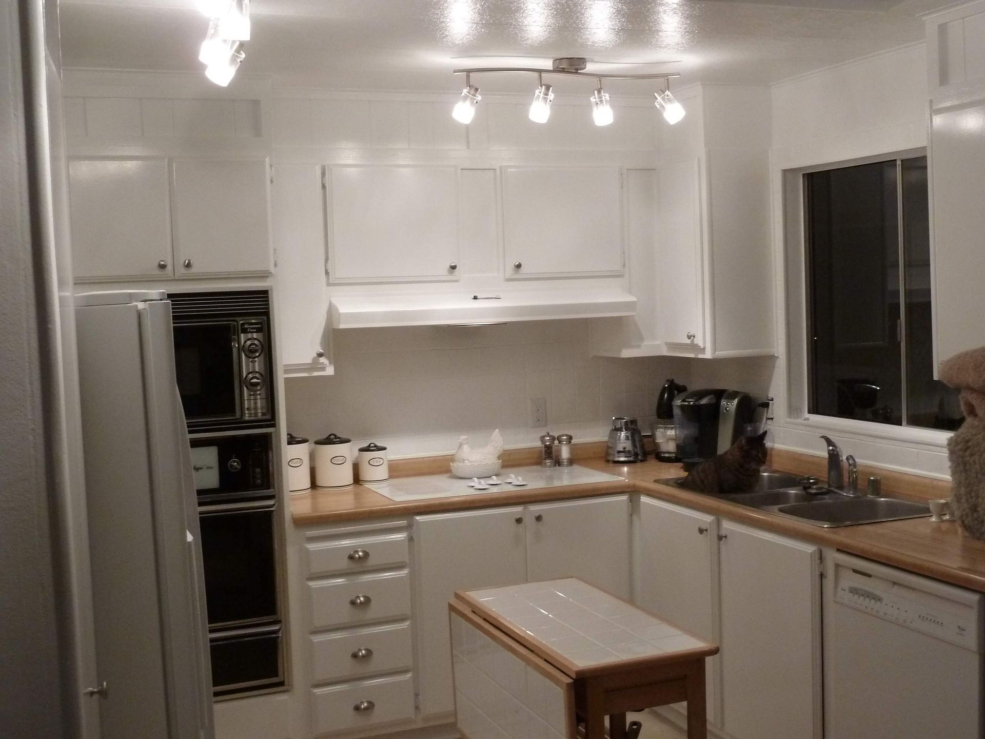 White kitchen with cabinets, appliances, and small table.