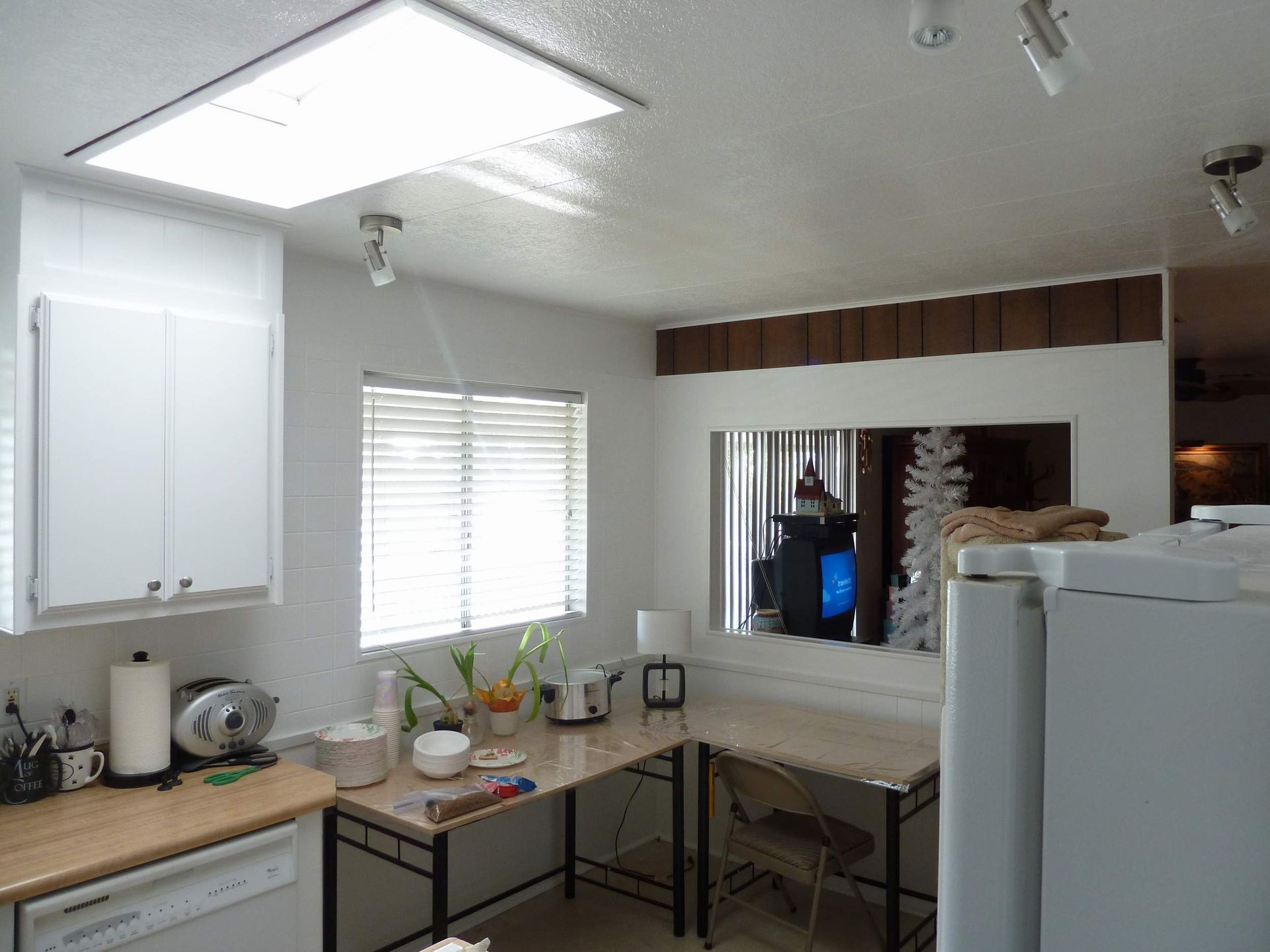 Bright kitchen with white cabinets, window, and desk area with a mirror.