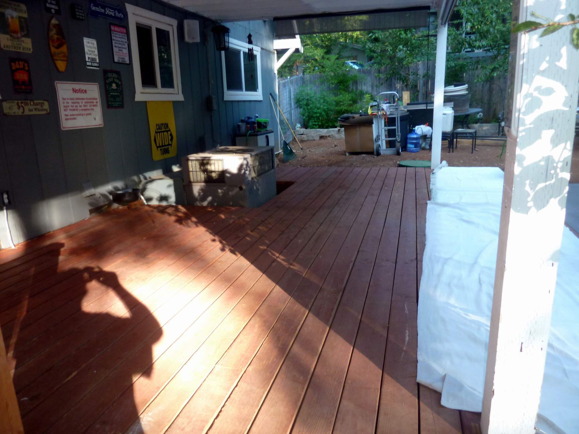 Wooden deck under a covered porch with shadow of a person holding a camera.