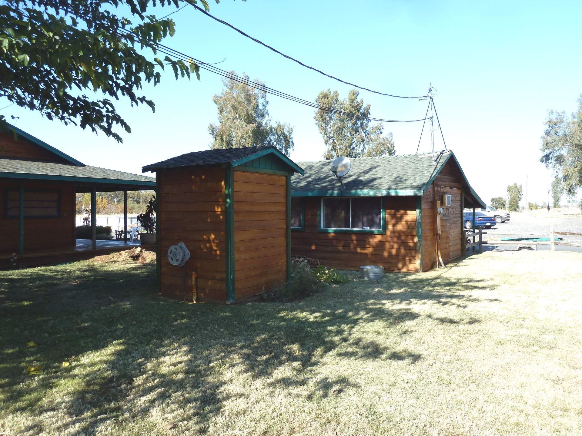 Wooden buildings with green roofs, brown siding, set on grassy land, blue sky background.