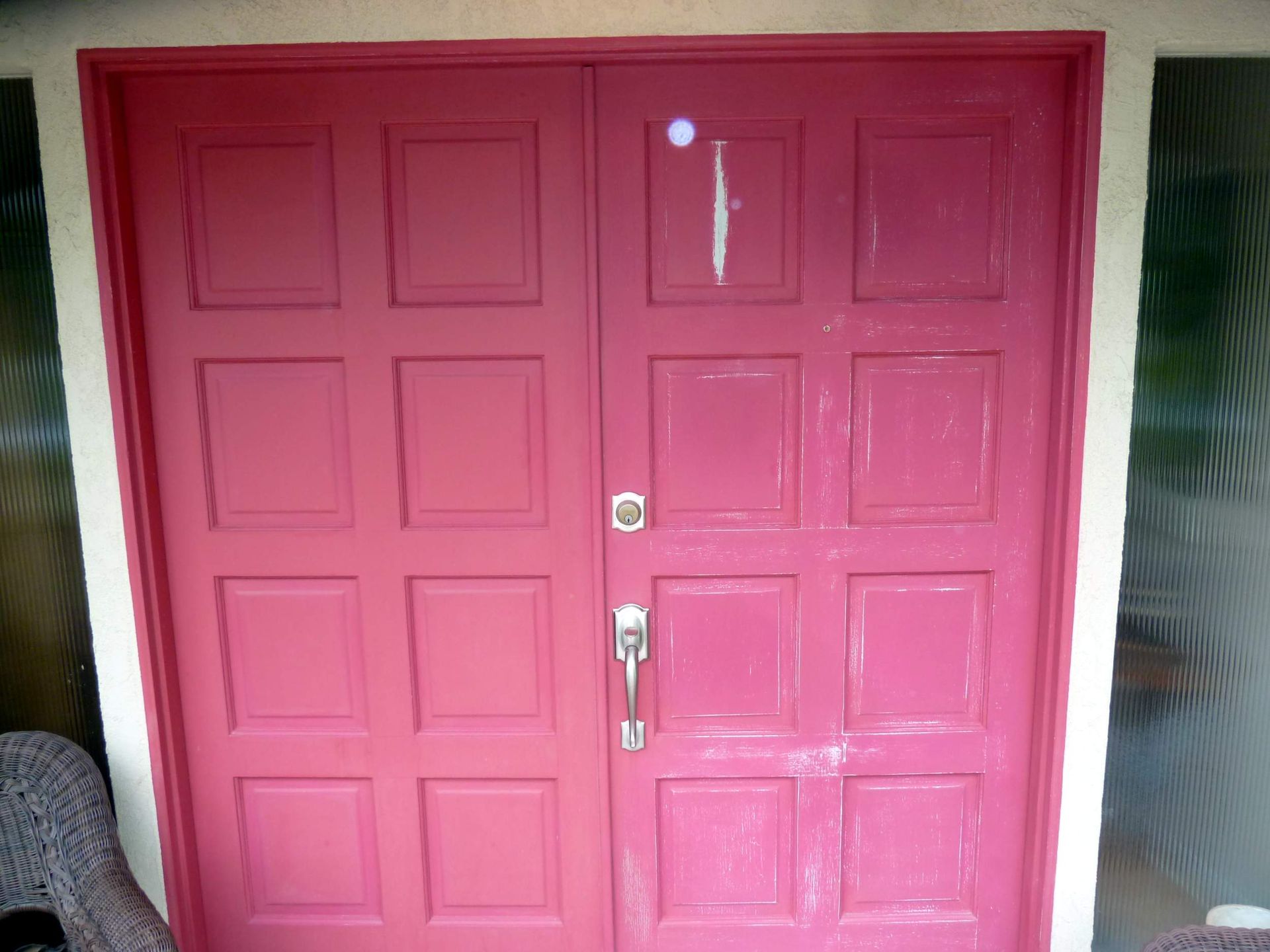 Pink double doors with rectangular panels; silver handle and lock.