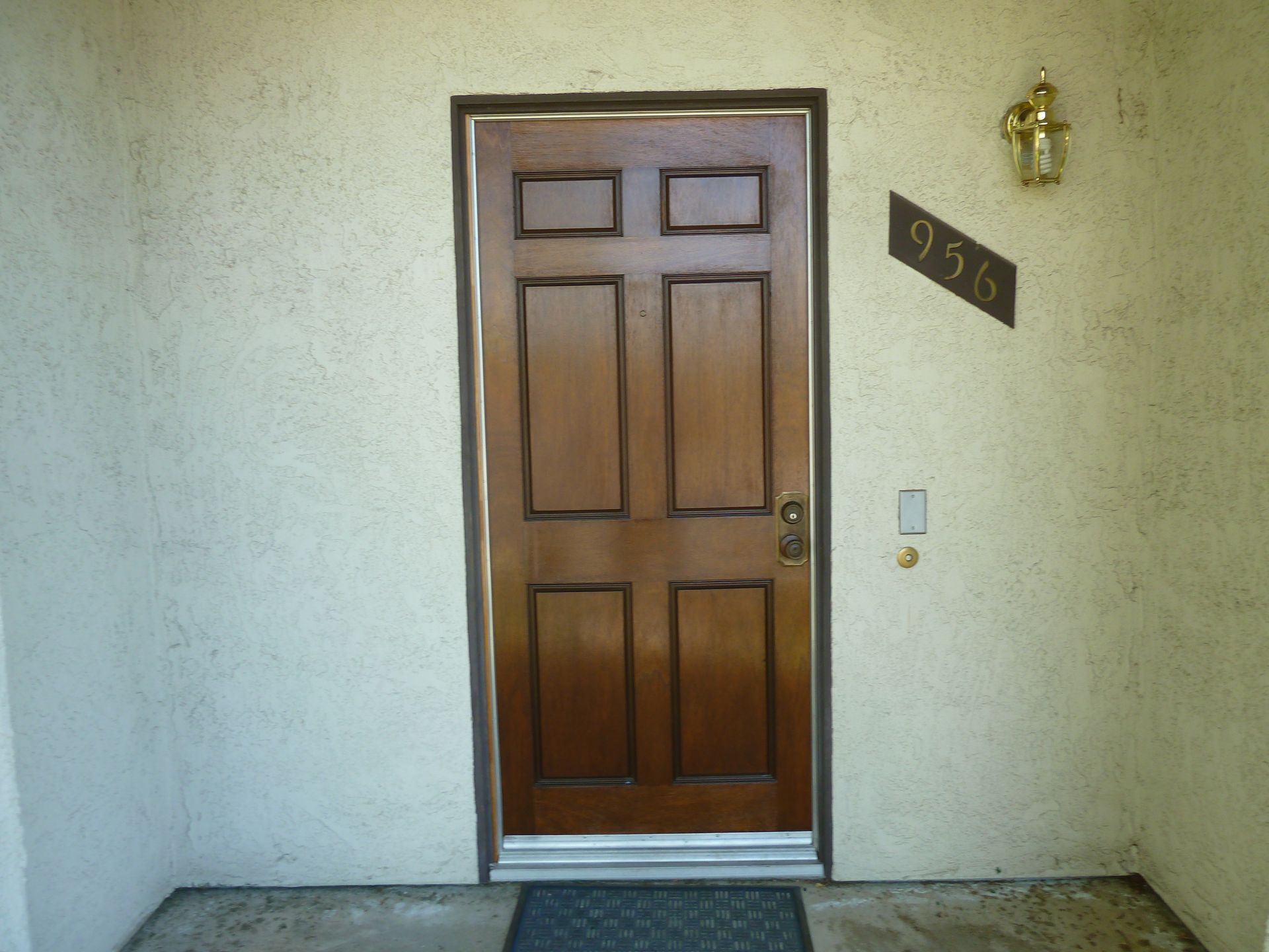 Brown door with six panels, a doorknob, and address plate 