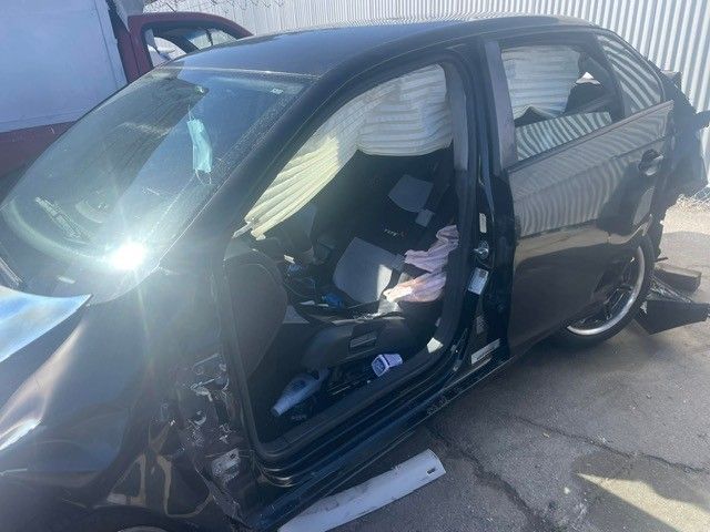Black car heavily damaged after a collision; airbags deployed.