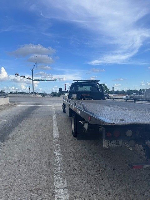 Tow truck parked on a road, under a blue sky with some clouds.