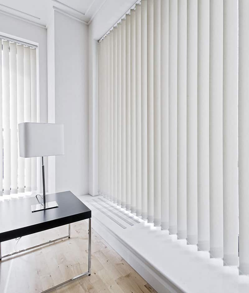 A Living Room With White Vertical Blinds and a Black Table — TT Shutters & Shading In Ballina, NSW