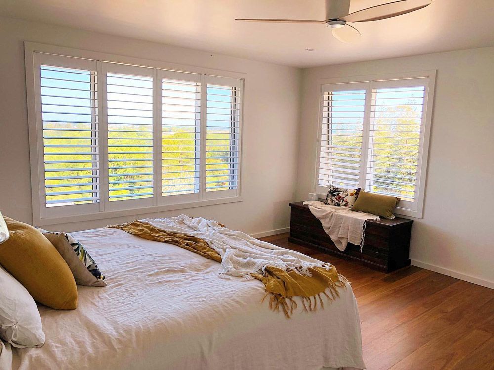 There is a Bed in the Middle of the Room With a Ceiling Fan— TT Shutters & Shading In Ballina, NSW