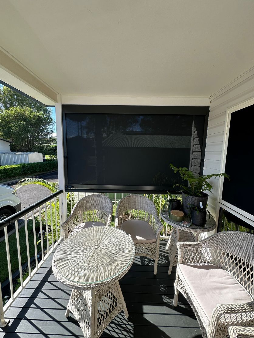 A Porch With Wicker Furniture and a Screened in Area — TT Shutters & Shading In Ballina, NSW