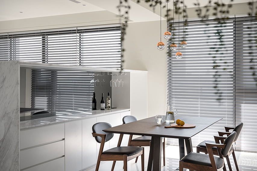 A Dining Room With a Table and Chairs in Front of a Window With Blinds — TT Shutters & Shading In Ballina, NSW