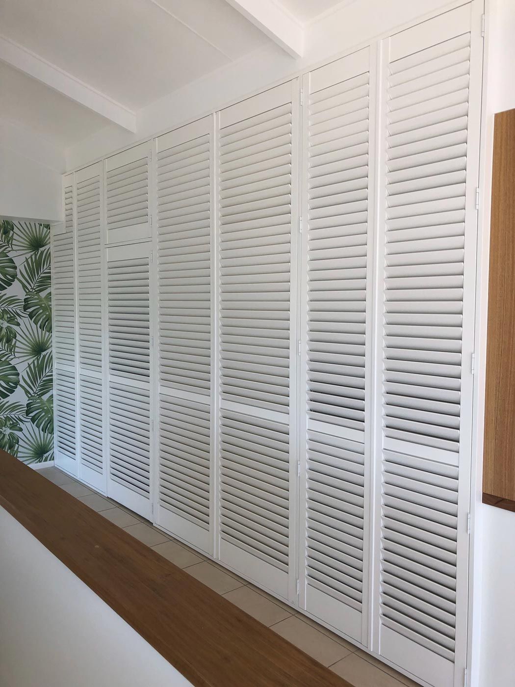 A Row of White Shutters on a Wall in a Room — TT Shutters & Shading In Ballina, NSW