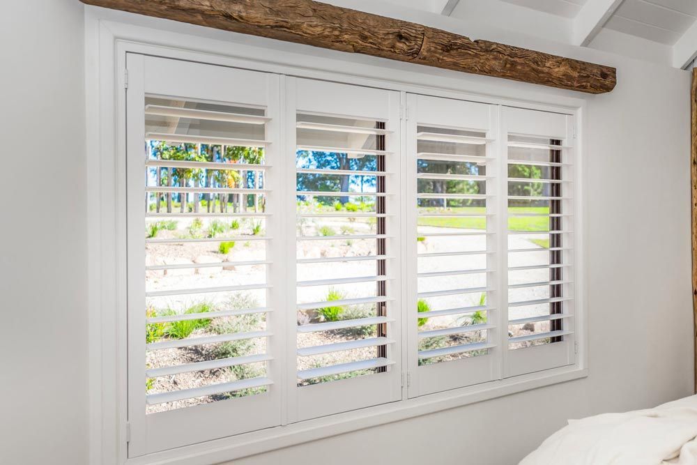 A Bedroom Window With White Shutters — TT Shutters & Shading In Ballina, NSW