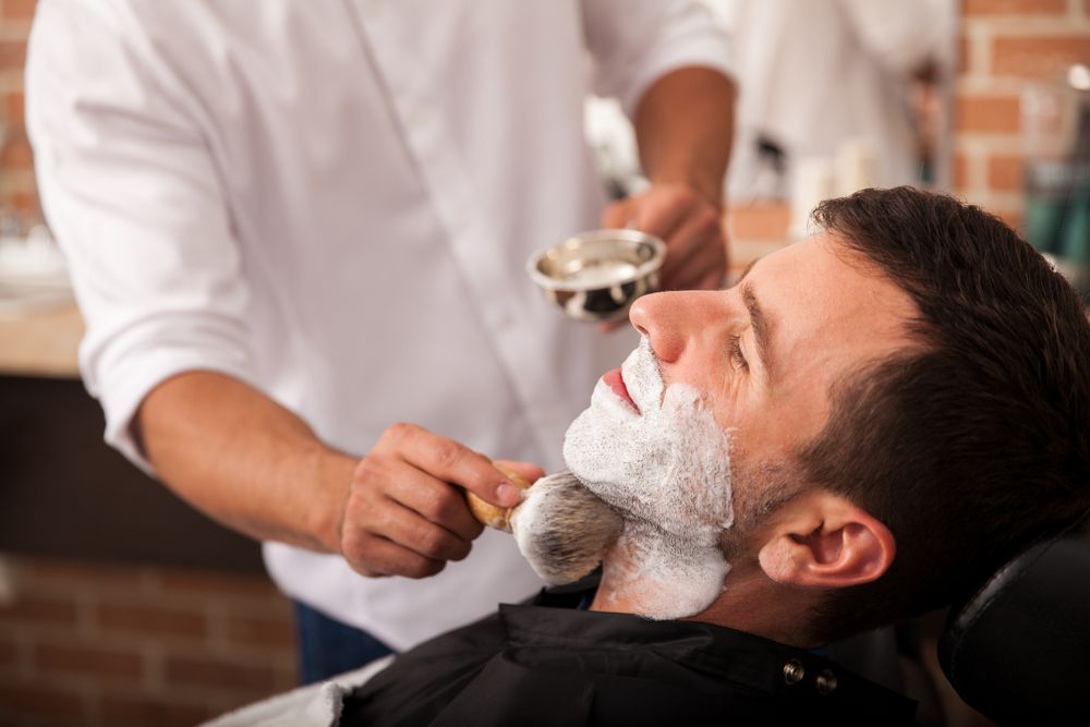 A Barber Applies Shaving Cream to A Client Face with A Brush at A Shop — The Barber Social In Raymond Terrace, NSW