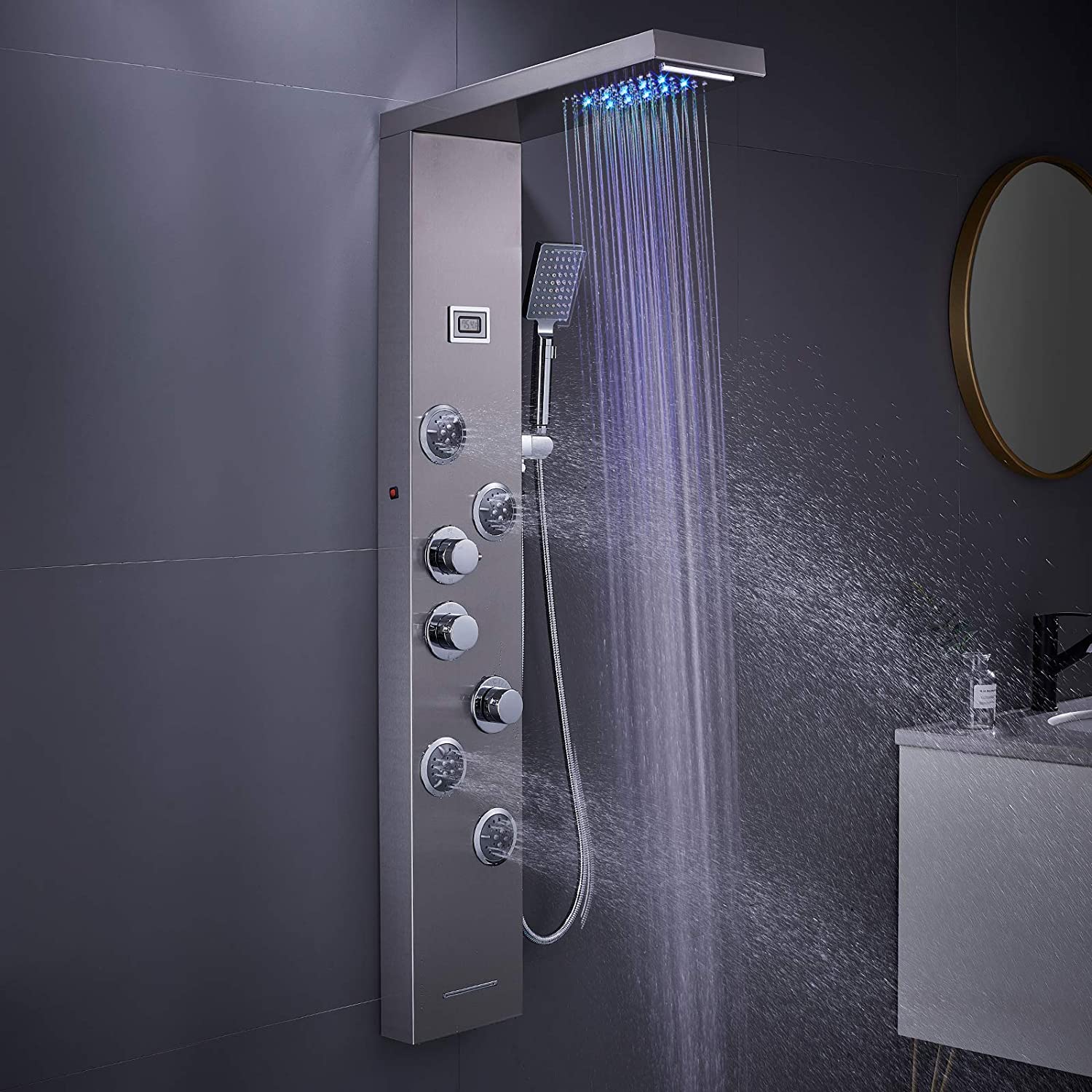 Modern shower panel with multiple shower heads and controls against a dark gray wall; water spraying.