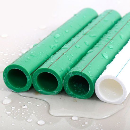 Green and white plastic pipes on a wet surface with water droplets.