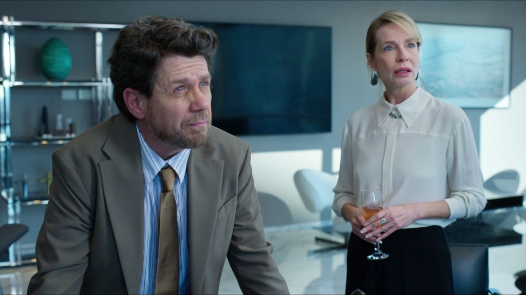 Hombre con traje marrón y mujer con camisa blanca en la oficina moderna.