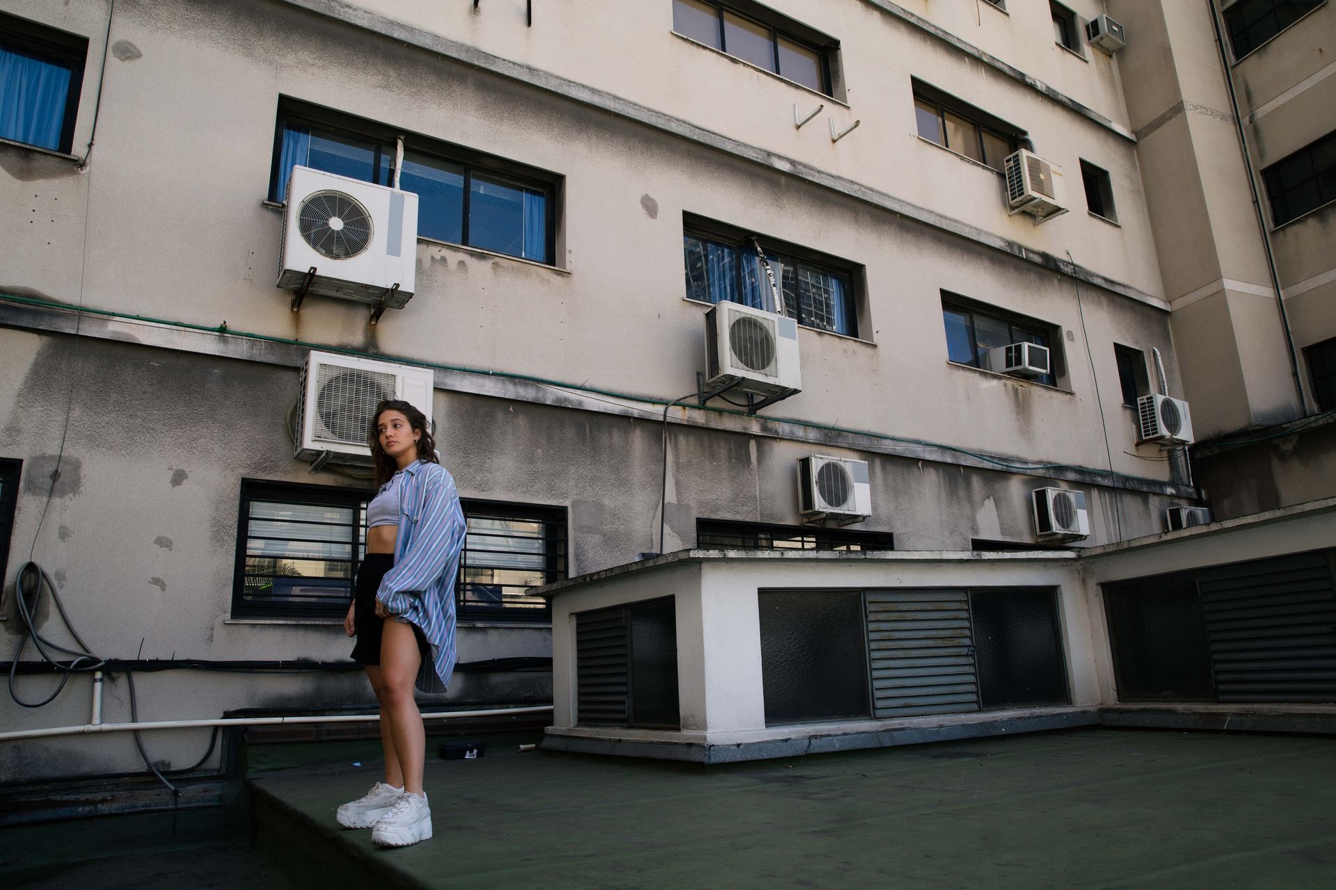 Una mujer con pantalones cortos y una camisa a rayas está parada en una azotea