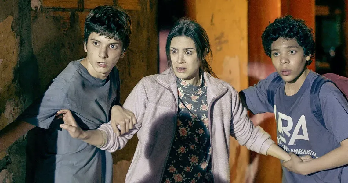 Una mujer y dos niños con expresiones temerosas se acurrucaron juntos en un callejón poco iluminado.