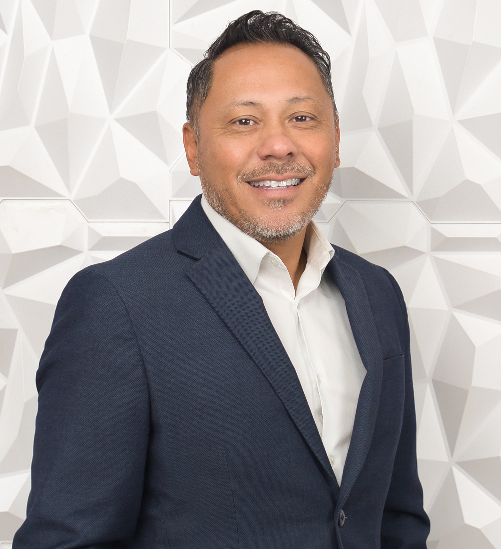 A man is sitting on a couch talking to two older people.