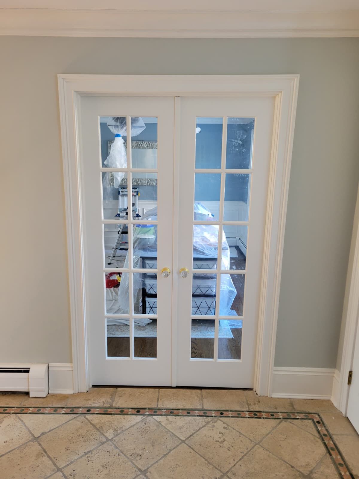 White French doors with multiple panes, leading into a room; tile flooring, light blue walls.
