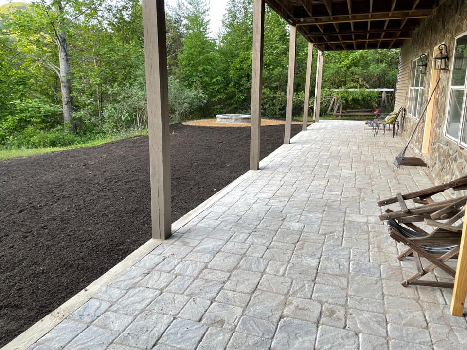 A brick walkway leading to a house with a covered porch