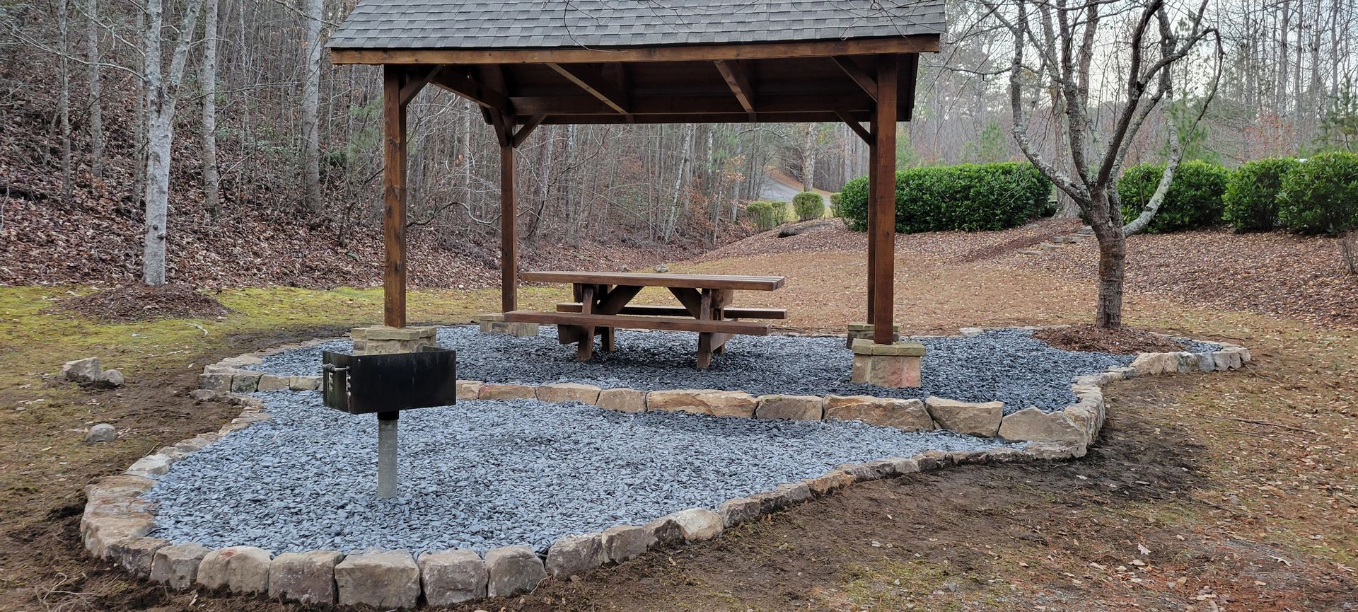 A wooden gazebo with a picnic table underneath it