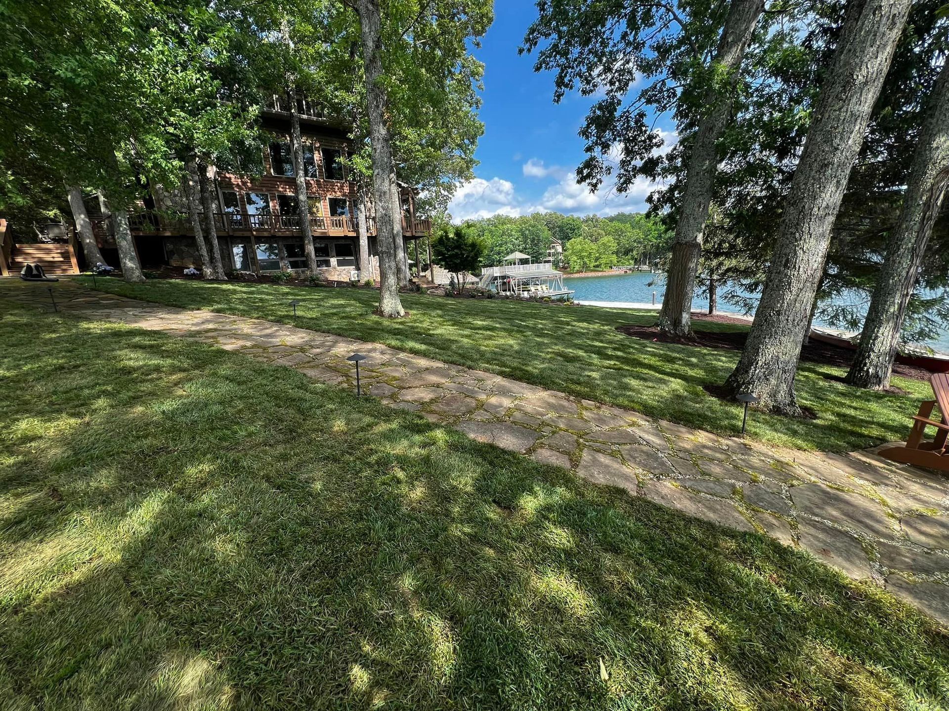 A path leading to a house next to a lake surrounded by trees.