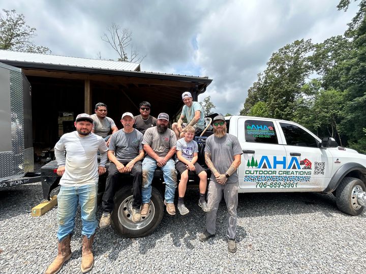 A group of men are sitting on the back of a truck.