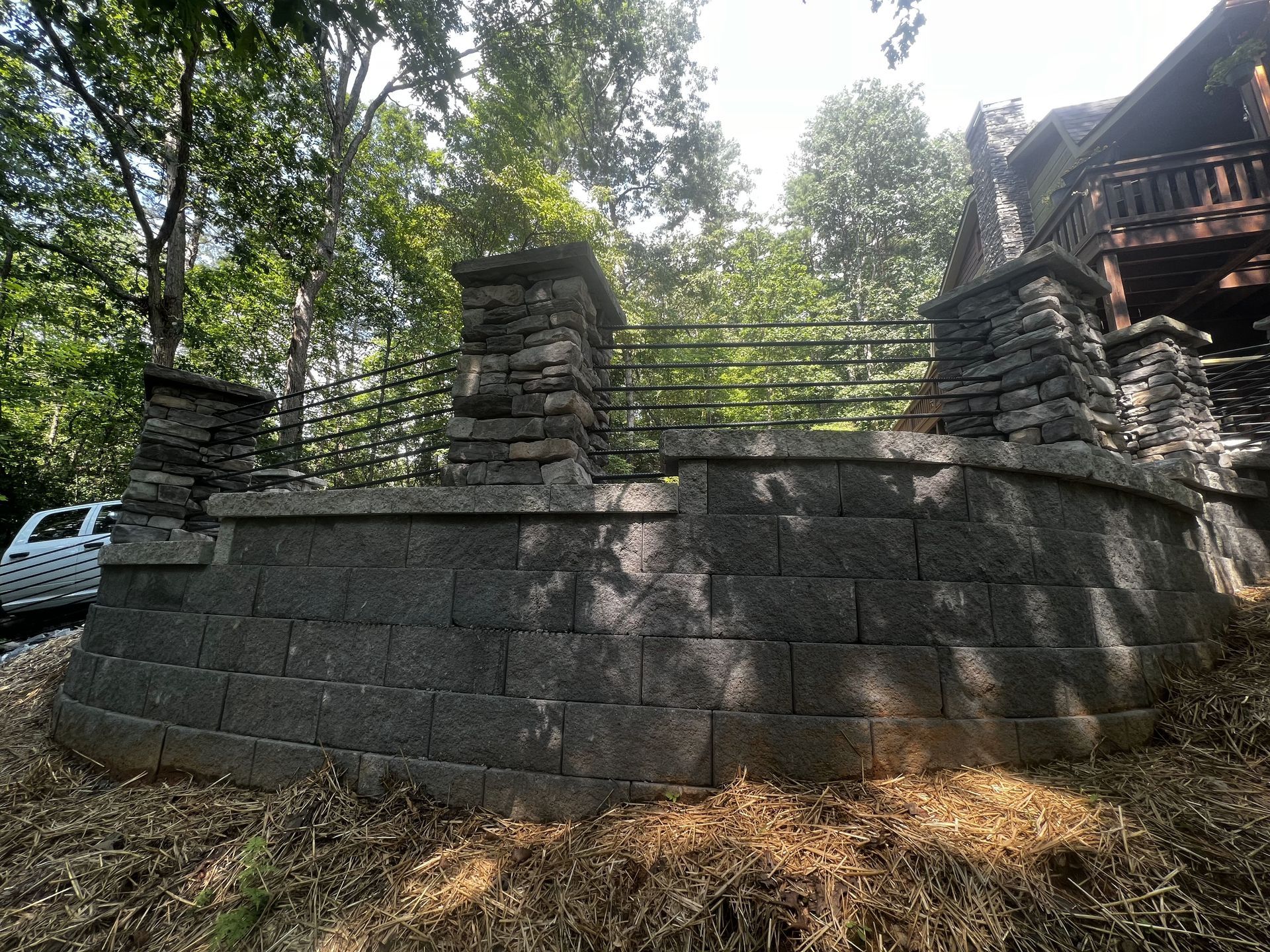 a large stone wall is surrounded by trees in front of a house .