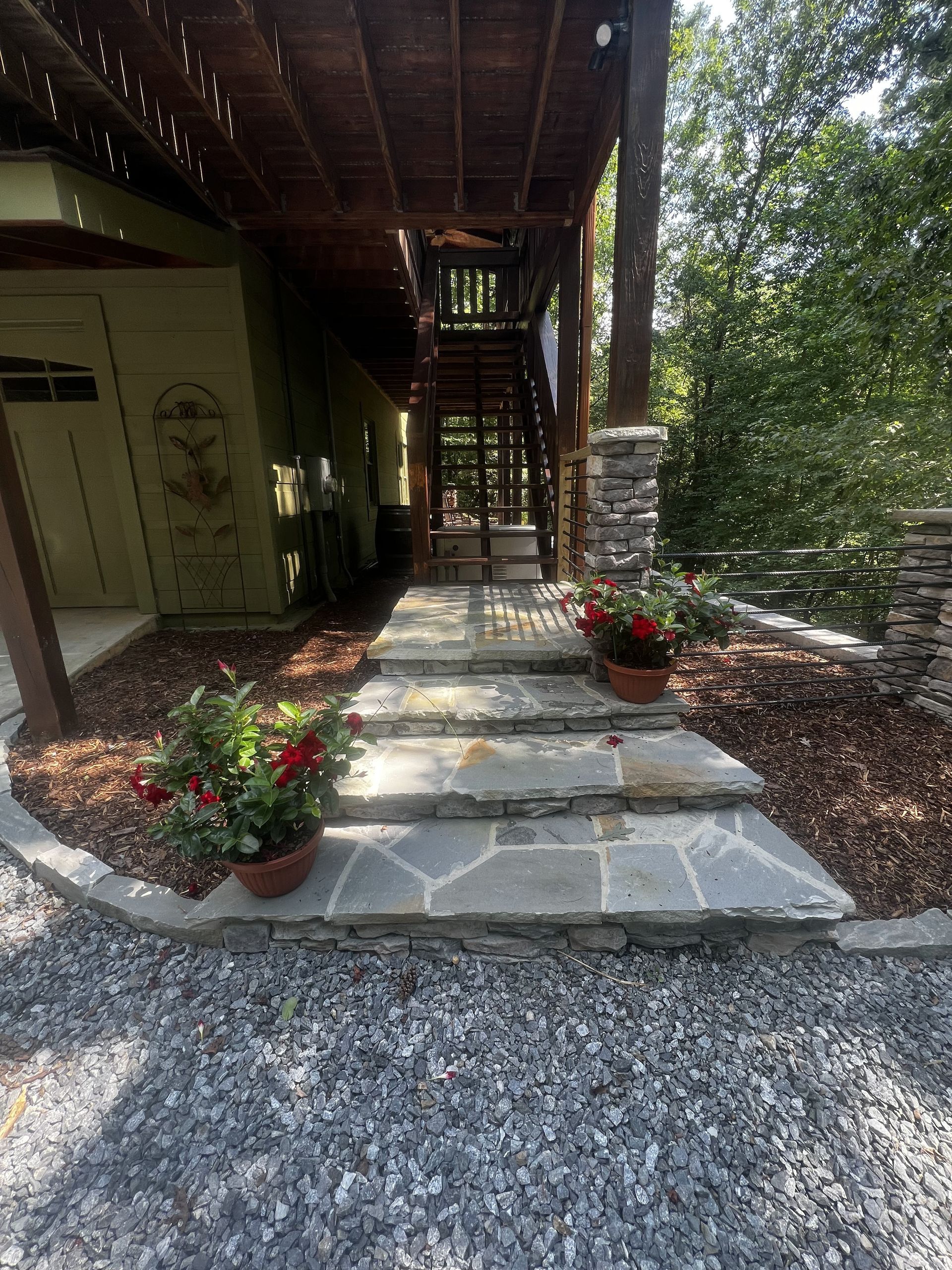 a stone walkway leading to a house with flowers in pots