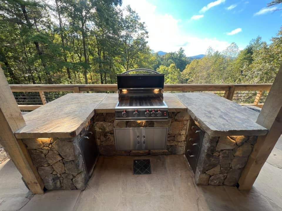 A grill is sitting on top of a stone counter on a patio.