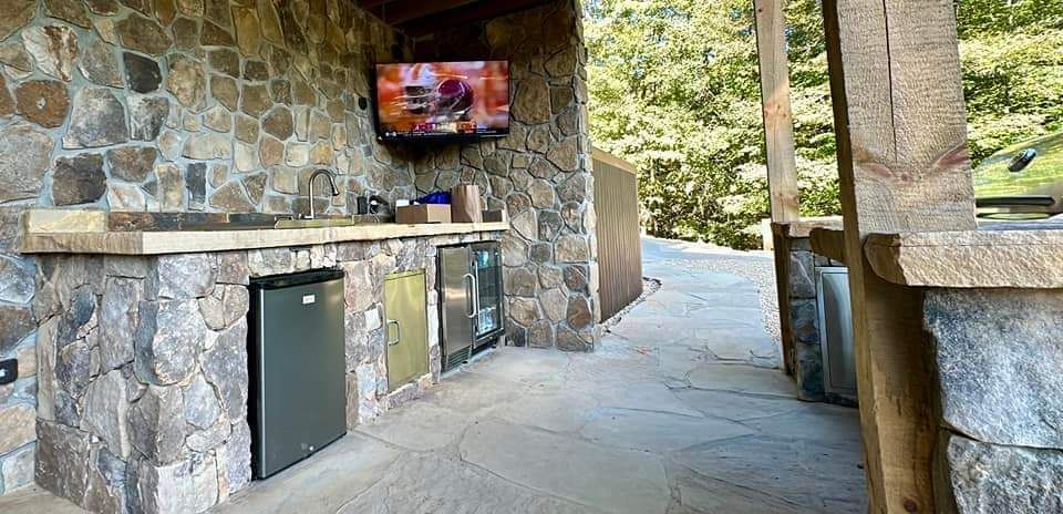 A stone kitchen with a flat screen tv mounted on the wall.