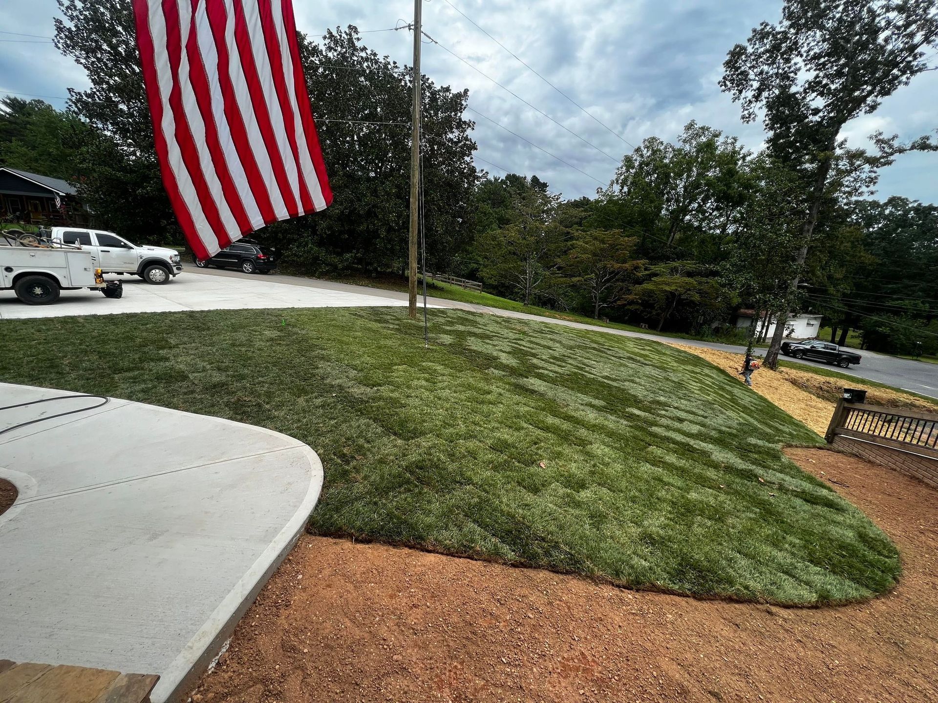 an American flag is flying in front of a lush green lawn