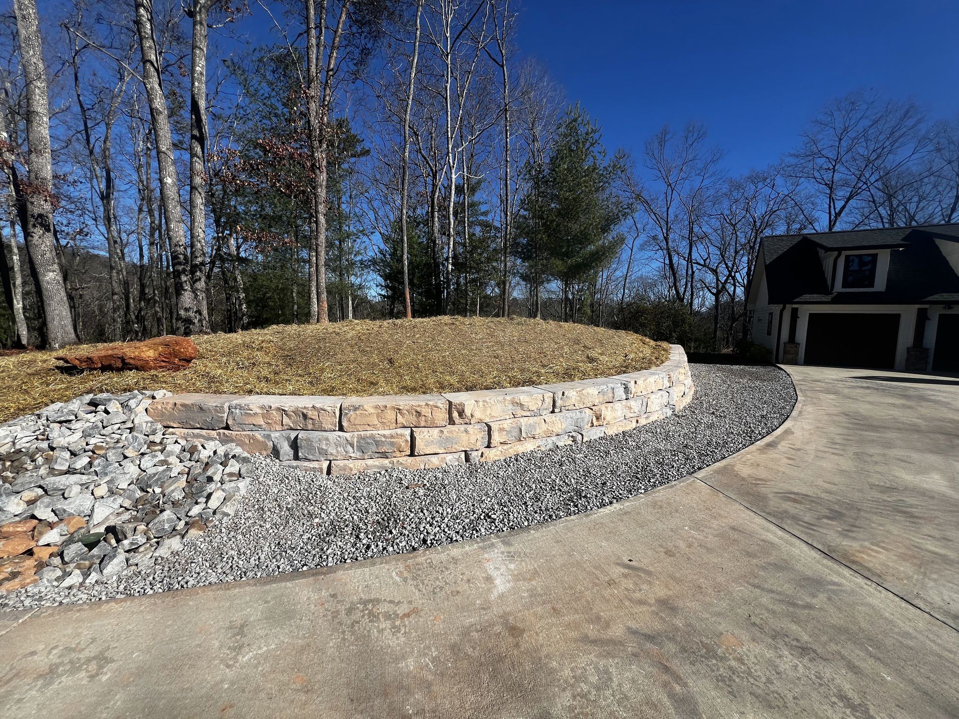 a driveway leading to a house with trees in the background