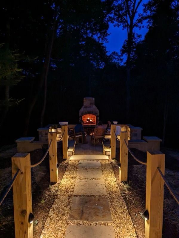 A stone walkway leading to a fireplace at night