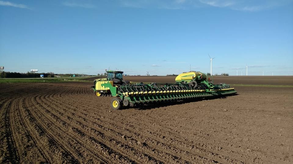 A john deere tractor is plowing a field.